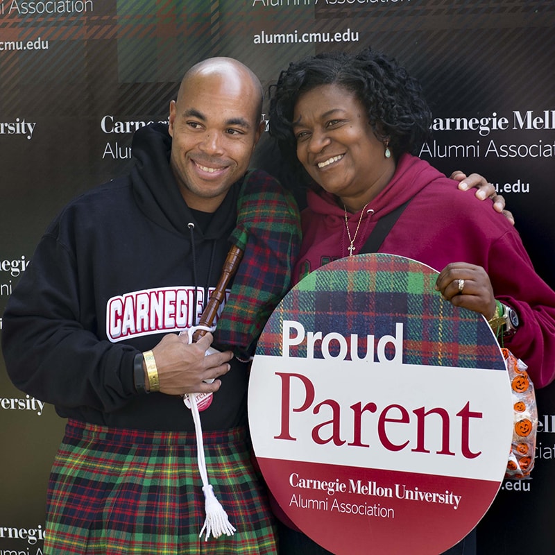 Photo of a student and his mother, holding a sign that reads 